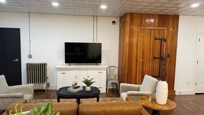 Una sala de estar con sofá, sillones, una mesa de centro y televisor.