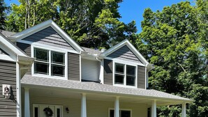 A two-story house with a covered porch, stone pillars, and a front yard with a lawn and shrubs. - Private 5 bedroom house in the heart of Laurel highlands! (Normalville)