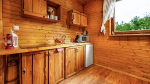 A wooden cabin kitchen with a wooden countertop, a sink, a microwave, and a refrigerator.