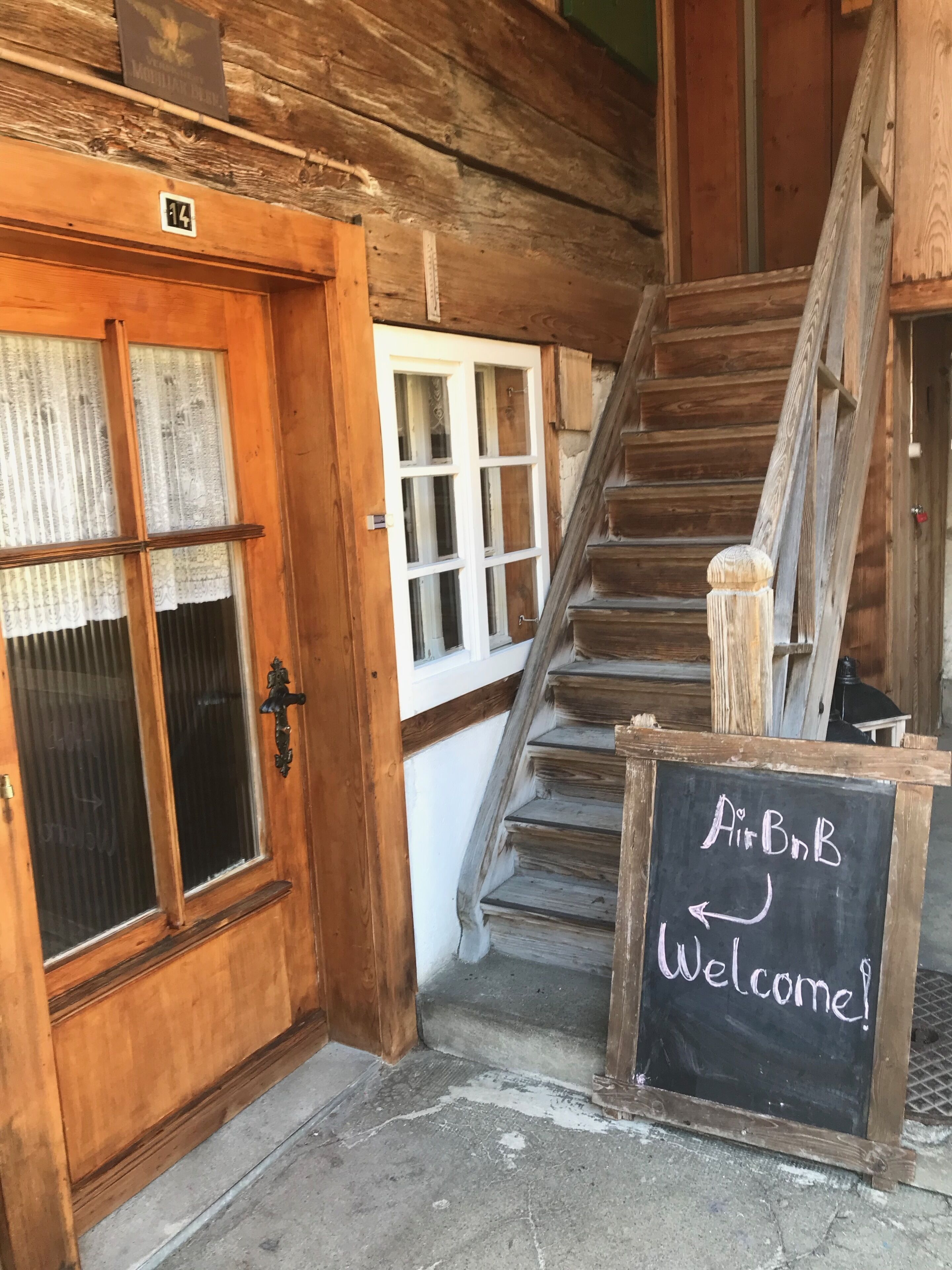 Un escalier en bois mène à une pièce où est affiché un panneau indiquant : « Bienvenue chez AirBnB ! ».
