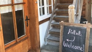 Una scala in legno conduce a una stanza con un cartello che dice 'AirBnB Welcome'.