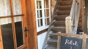 Un escalier en bois mène à une pièce où est affiché un panneau indiquant : « Bienvenue chez AirBnB ! ».