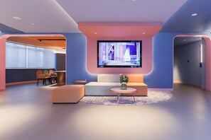 Un área de estar moderna con televisor de pantalla plana, asientos y comedor.