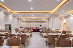 A conference room with tables and chairs, a person standing near the tables, and a buffet area in the background. - Vienna International Hotel (Chizhou High‑Speed Railway Station, ) (Chizhou)