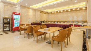 Uma área de refeições de hotel, com mesas, cadeiras, máquina de venda automática e balcão de buffet.