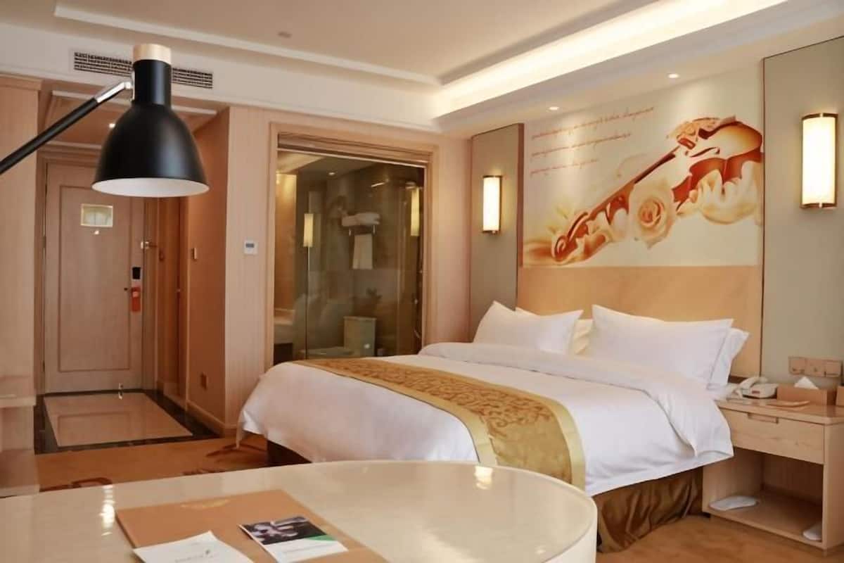 Une chambre d’hôtel avec un lit, une table de chevet, une lampe et un mur orné d’un motif floral.
