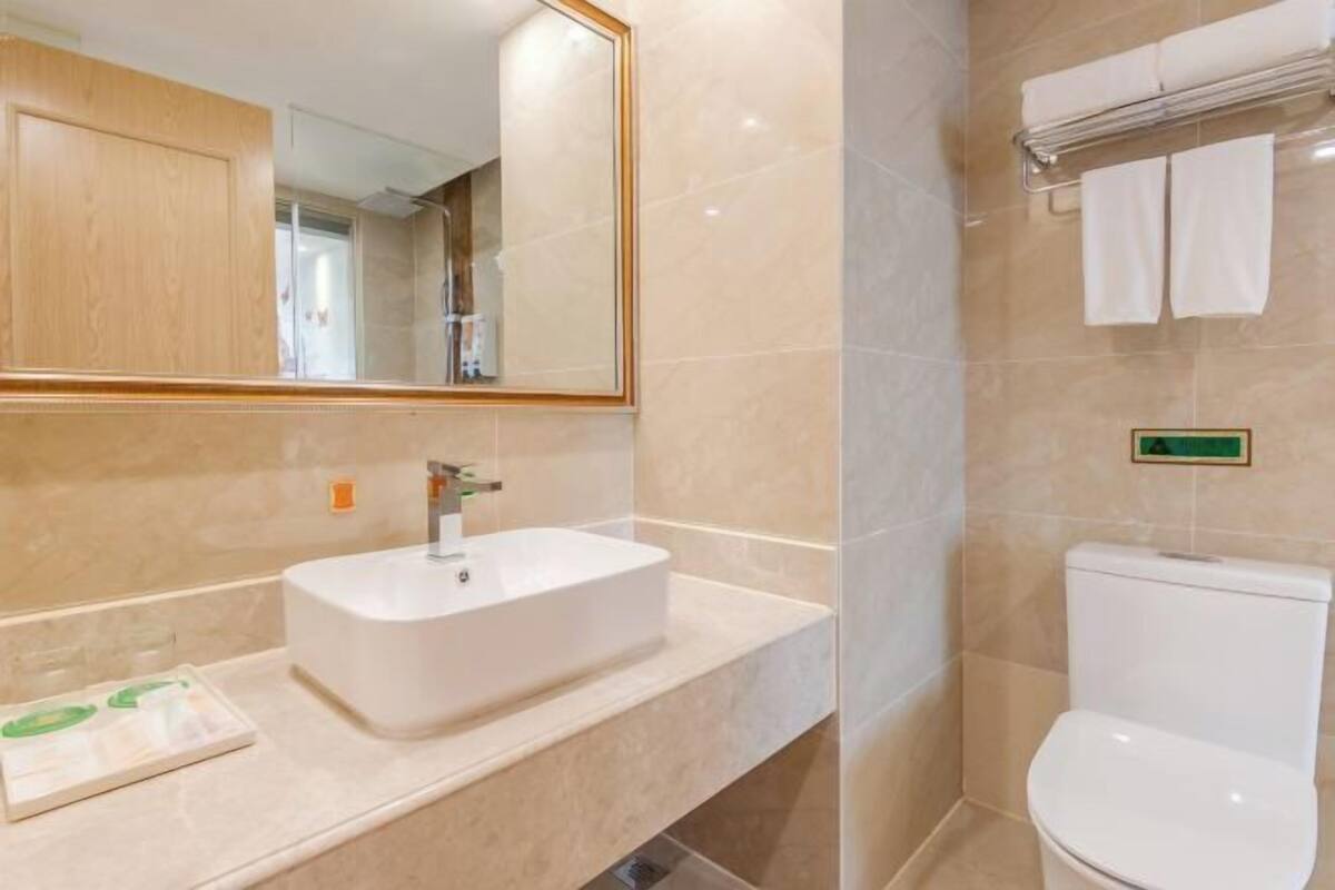 Une salle de bain avec un lavabo blanc, un miroir et des toilettes.