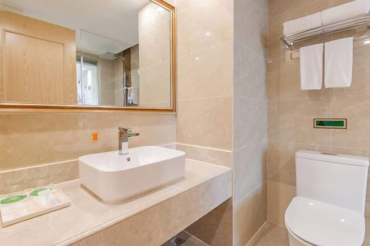 A bathroom with a white sink, mirror, and toilet.
