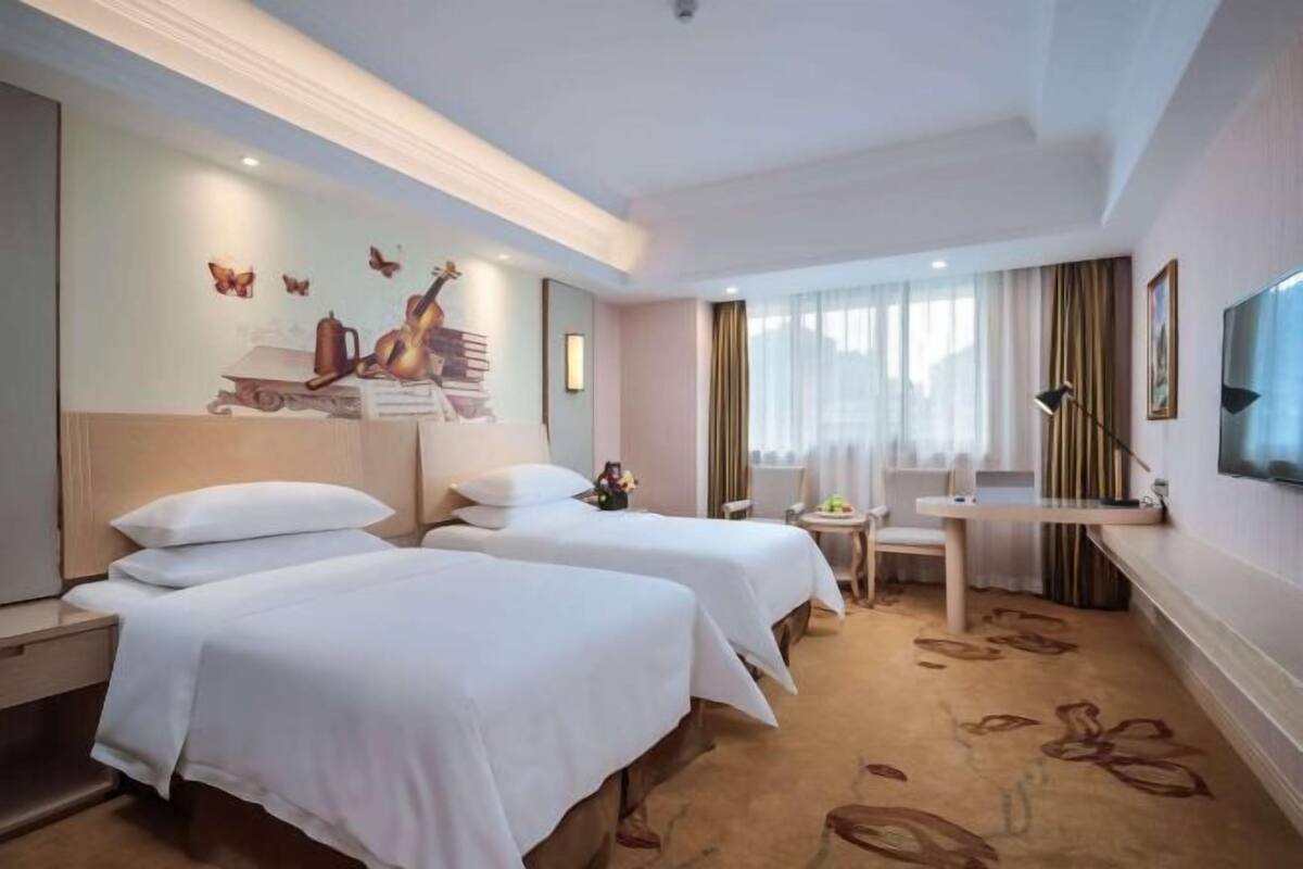 Une chambre d’hôtel avec deux lits, un bureau, une chaise, une télévision et une fresque murale.