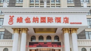 Entrada de hotel com placa em caracteres chineses, colunas imponentes e estilo arquitetônico clássico.