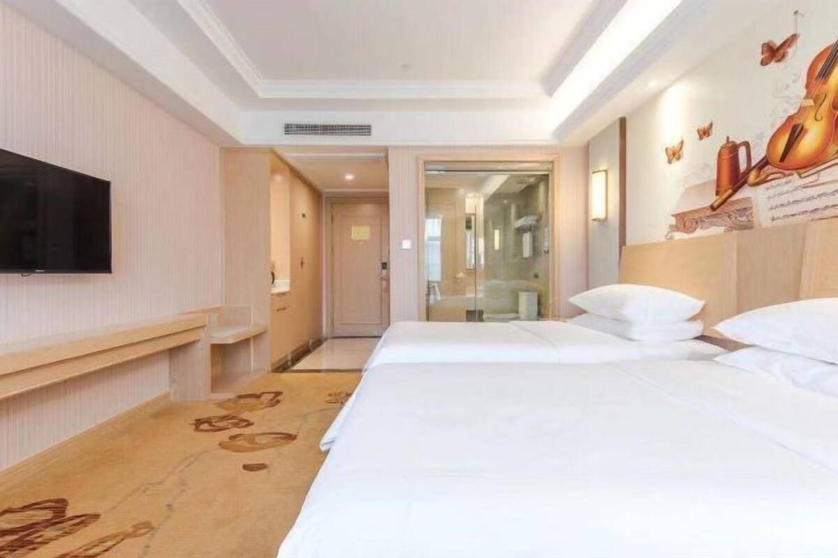 Une chambre d’hôtel dotée d’un grand lit, d’un téléviseur à écran plat fixé au mur et d’une fresque décorative.