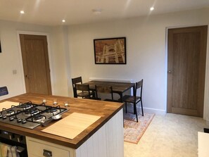 A kitchen with a central island, a dining table with chairs, and a framed picture on the wall.