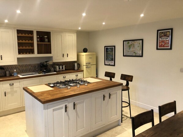 A modern kitchen with white cabinetry, a wooden island, and bar stools.