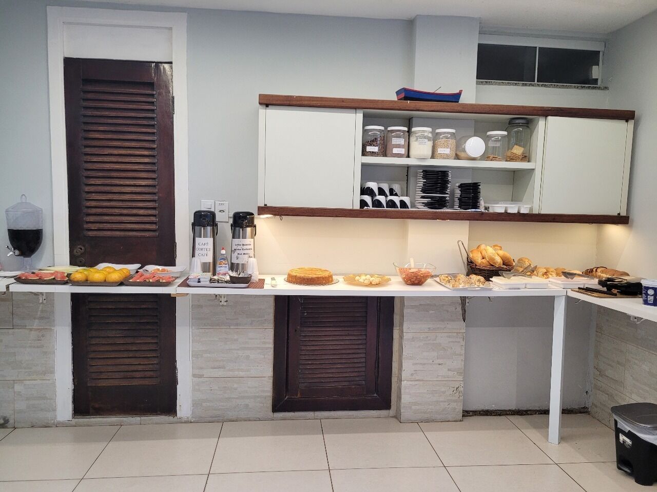 A kitchen with a coffee machine, jars, and a variety of food items on the counter.