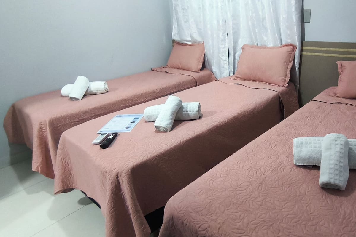 Hotellihuoneessa on kaksi sänkyä, joissa on molemmissa vaaleanpunainen peitto ja tyynyt. Jokaisessa sängyssä on siististi taiteltuja pyyhkeitä.