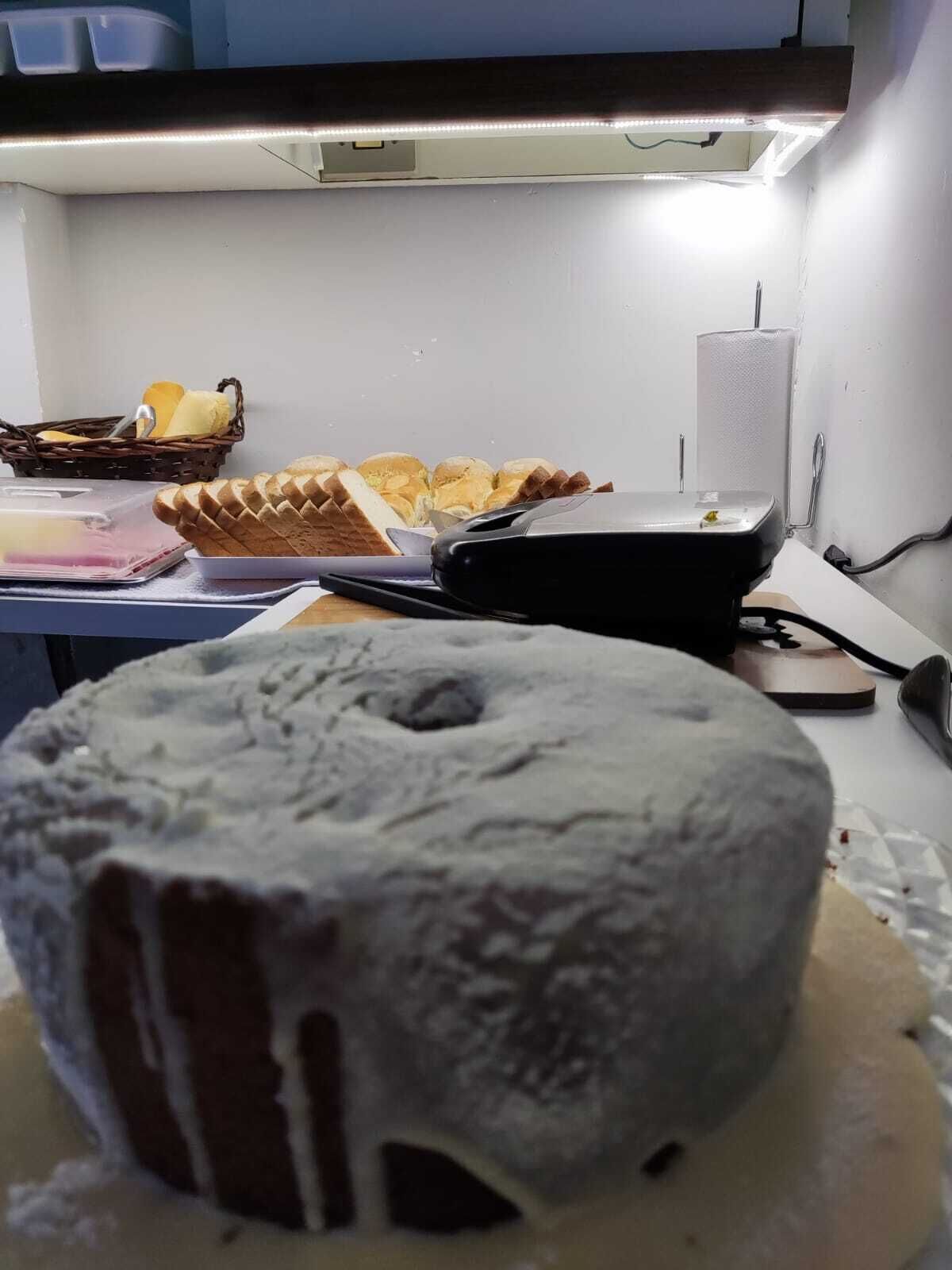 Una cocina con un pastel Bundt en una bandeja para hornear, una hogaza de pan y una cesta de queso.