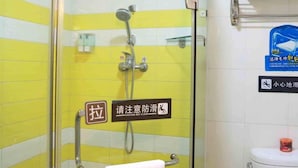 Un baño con cabina de ducha de vidrio, un perchero y un inodoro con dispensador de jabón.