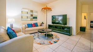 A living room with a sofa, coffee table, TV, and a decorative floor lamp. - Blue Ocean Vacation Rentals at Las Verandas️ ️ (South Padre Island)