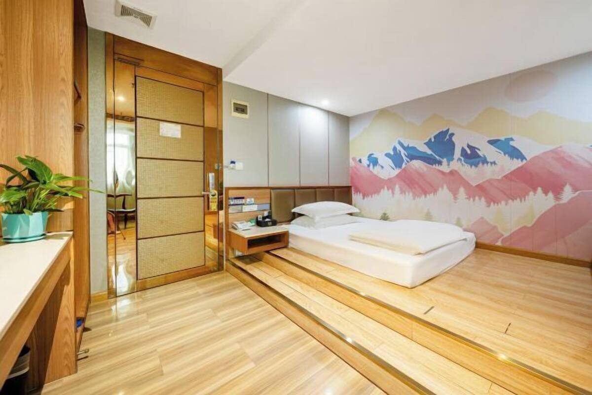 Un dormitorio moderno con piso de madera, una cama, una mesita de noche, una planta en maceta y una puerta corredera.