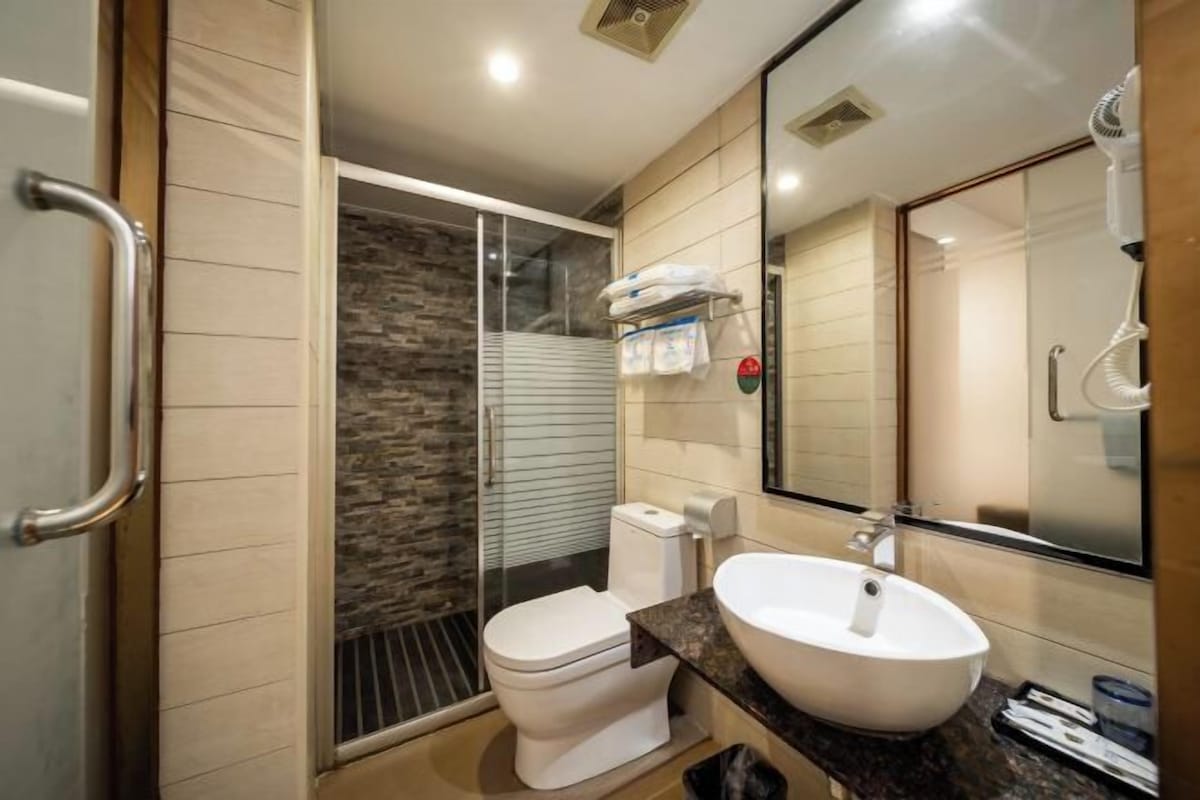 Une salle de bain moderne avec une douche à parois de verre, des toilettes blanches et un grand lavabo avec un miroir.