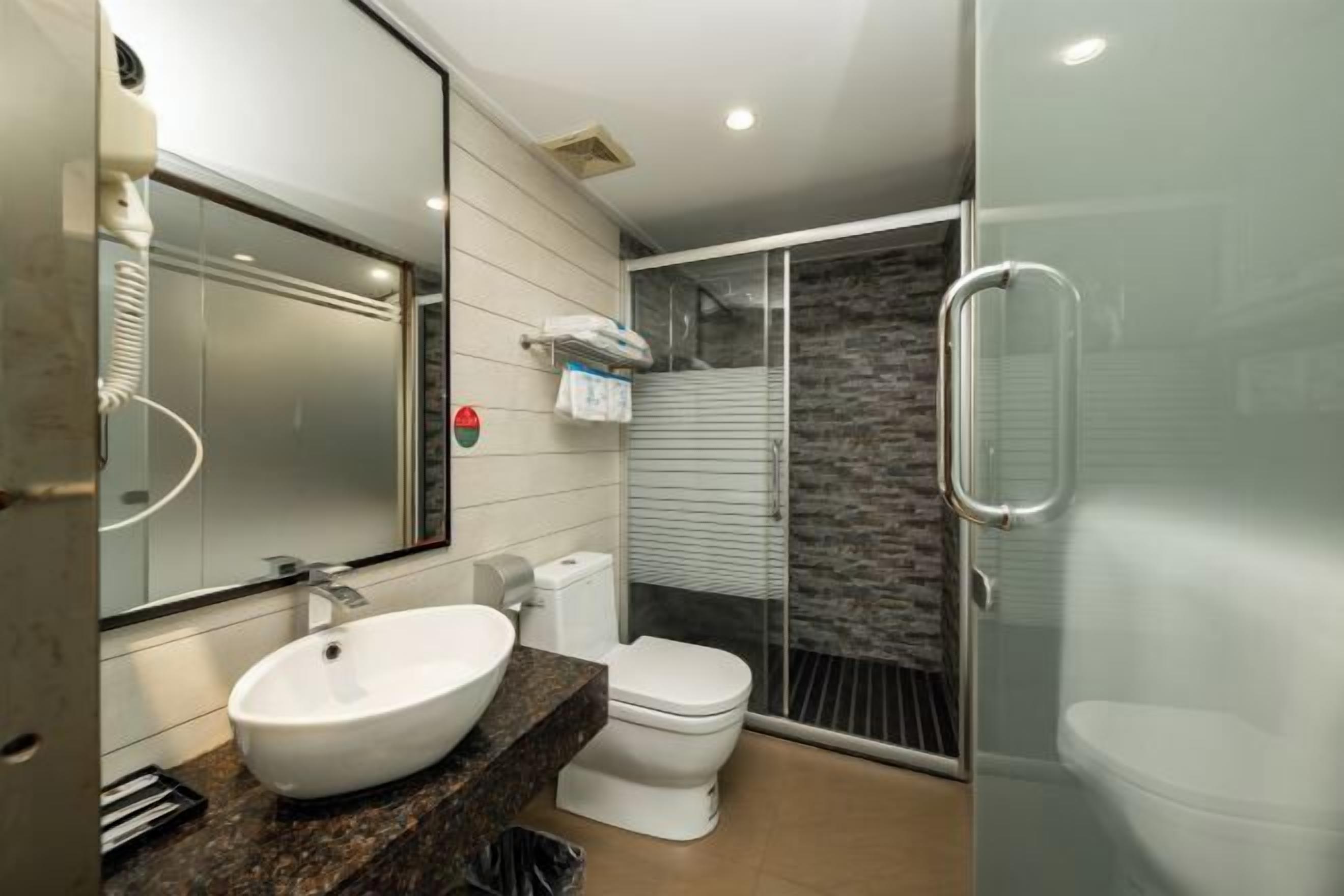 A modern bathroom with a large mirror, white sink, and toilet.
