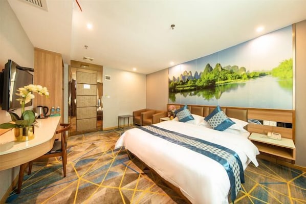 Une chambre d’hôtel avec un grand lit, un bureau avec une chaise, une télévision et un tableau représentant un paysage accroché au mur.