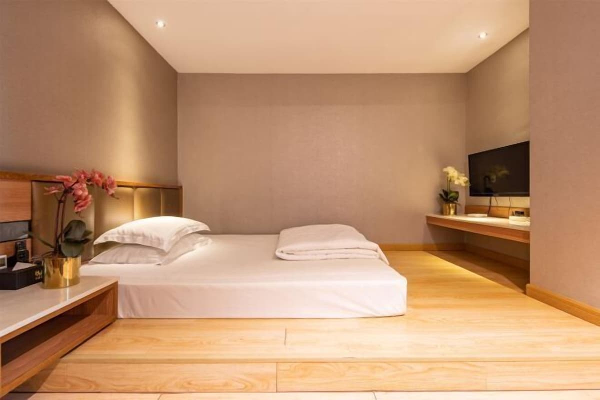 Une chambre d’hôtel moderne avec un lit, une télévision et un plancher en bois.