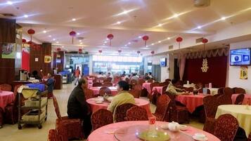 A spacious dining hall with round tables, red and white tablecloths, and red lanterns.