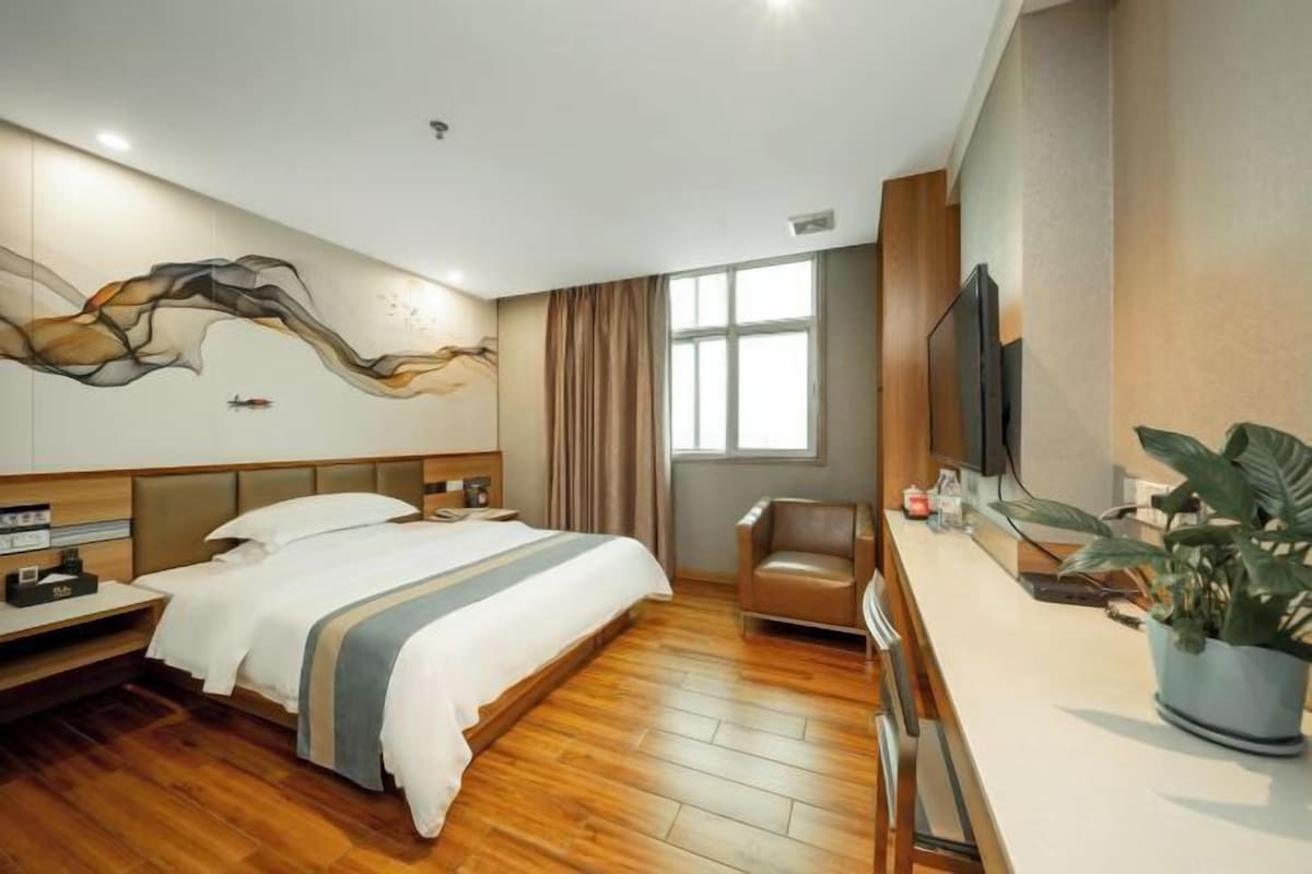 Une chambre d’hôtel moderne équipée d’un grand lit, d’un bureau, d’une chaise, d’une télévision et d’une fenêtre.