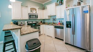A kitchen with white cabinets, stainless steel appliances, and a granite countertop.