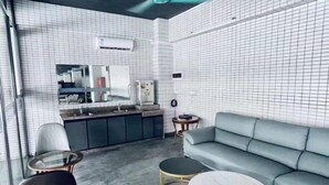 A modern living room with a grey sofa, two round coffee tables, and a glass table. - Haihe Business Hotel (Enping)