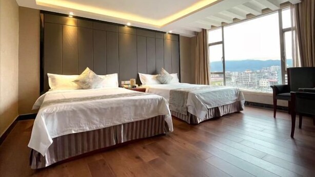 A hotel room with two beds, a large window with a city view, and a modern ceiling design. - Haihe Business Hotel (Enping)