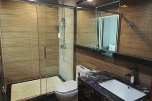 Un baño moderno con ducha vidriada, inodoro blanco y lavamanos de mármol.