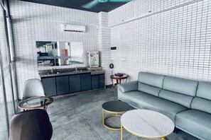 A modern interior with a kitchenette, a sofa, and a round coffee table. - Haihe Business Hotel (Enping)