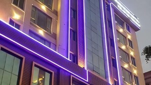 A multi-story building with illuminated vertical lines and windows. - Haihe Business Hotel (Enping)