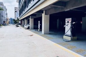 A parking garage with concrete pillars, a white car, and a charging station. - Haihe Business Hotel (Enping)
