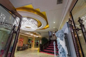 Un hall d’hôtel avec un grand escalier, un lustre et un comptoir d’accueil.