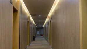 Un couloir d’hôtel avec un sol recouvert de moquette, des portes des deux côtés et un panneau indiquant la sortie.