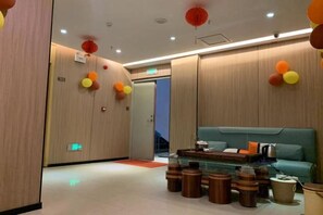 Un moderno vestíbulo de hotel con mostrador de recepción, zona de estar y una escalera.