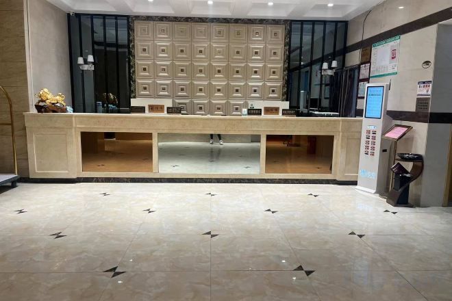 A reception area with a counter, seating, a wall-mounted information board, and a floor with a geometric pattern.