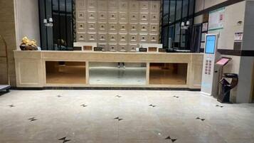 A reception area with a counter, seating, a wall-mounted information board, and a floor with a geometric pattern.
