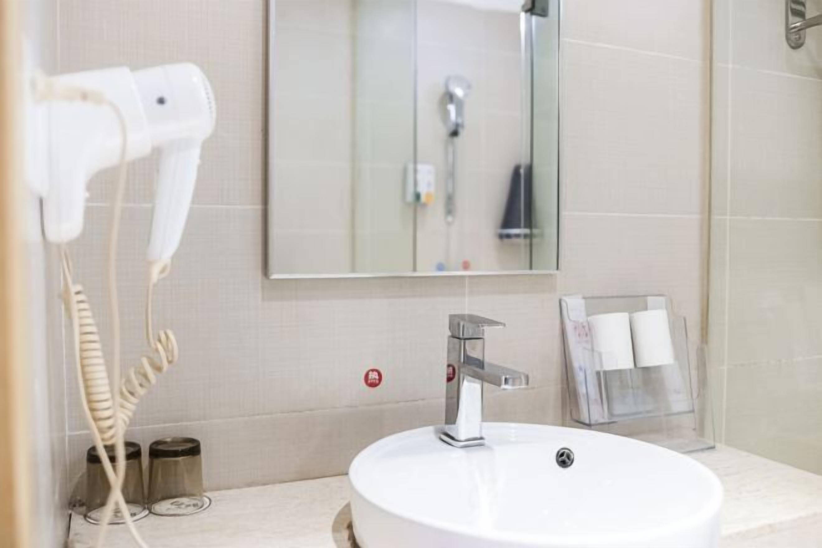 Une salle de bain avec un lavabo rond, un miroir, un sèche-cheveux et un porte-serviettes.