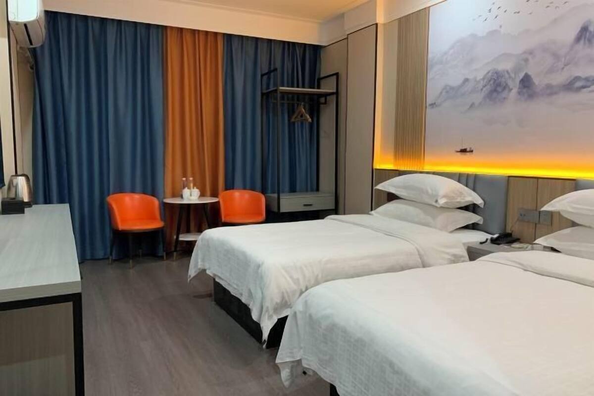 Habitación de hotel con dos camas, un escritorio, una silla, una mesita y un cuadro en la pared.