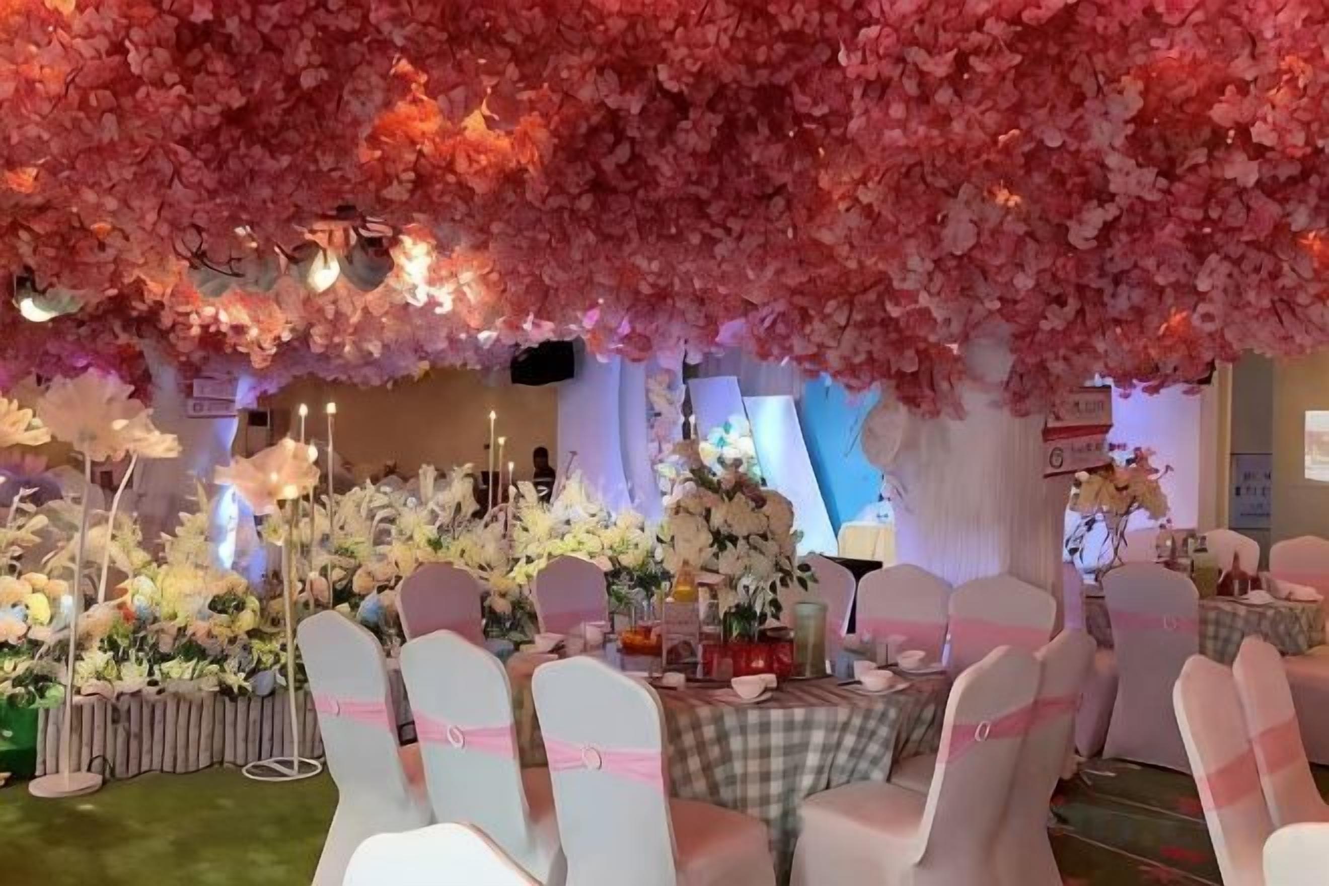 A banquet hall with round tables, white chairs, and floral decorations.