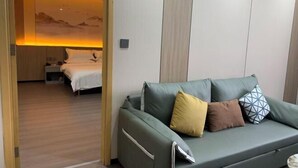 Une chambre d’hôtel moderne avec un canapé vert, un lit avec une literie blanche et une œuvre d’art accrochée au mur.