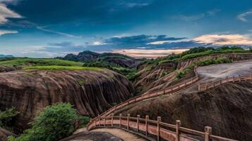 A landscape with terraced hills, a wooden bridge, and a clear sky.