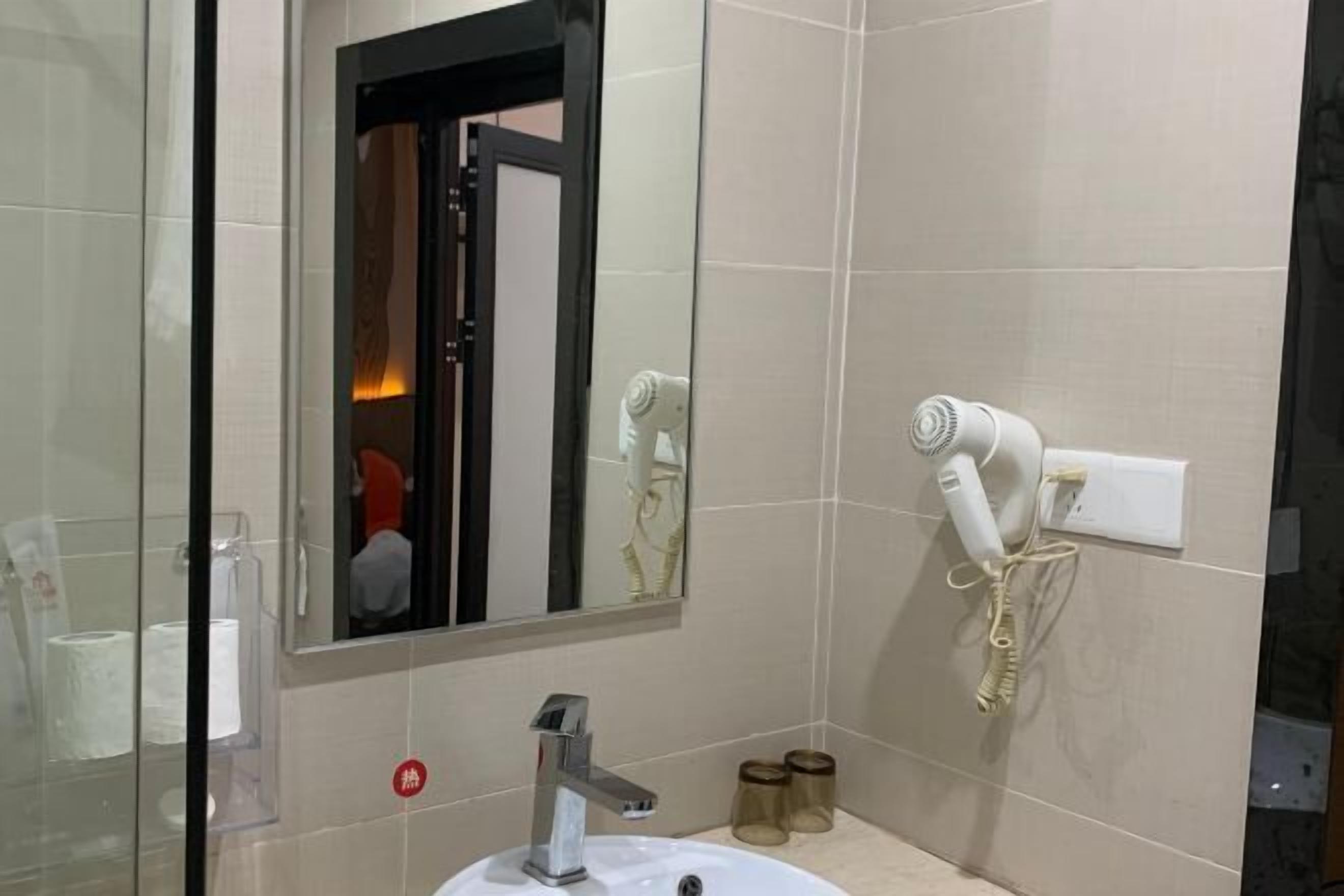Ein Badezimmer mit Waschbecken, Spiegel und zwei an der Wand montierten Haartrocknern.