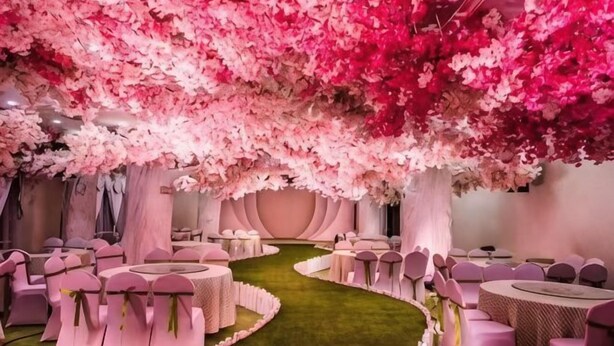 Un espace doté de tables et de chaises rondes, d’une allée centrale et d’un décor floral rose en arrière-plan.