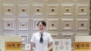 Un comptoir d’accueil d’hôtel avec un caissier et des panneaux indiquant la réception.