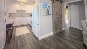 Une cuisine moderne avec des armoires blanches, un grand réfrigérateur et un plancher en bois.
